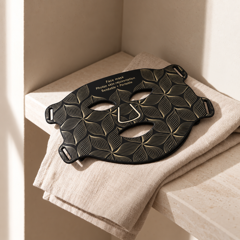 Aurora Light Mask in black resting on folded linen in a stone niche