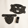 Aurora Light Mask in black: face mask, neck and decollete piece and remote control laid out on a cream background